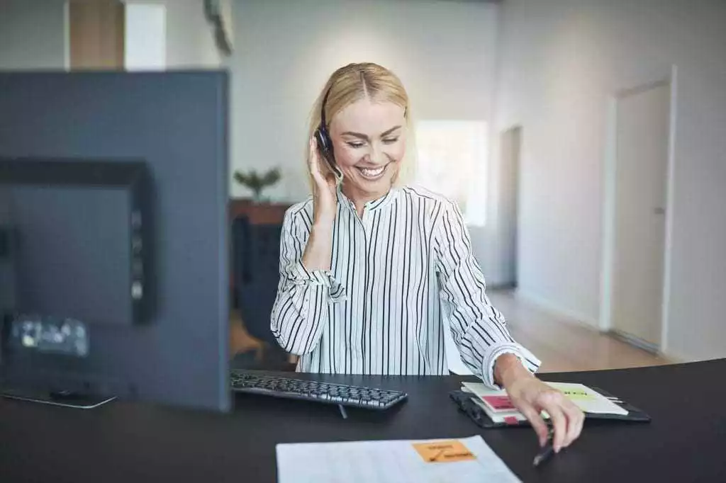 Laughing businesswoman talking on a headset at her office desk