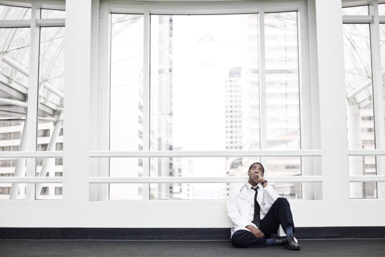 black man doctor stressed out and sitting on floor