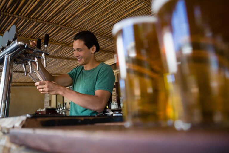close up of beer glasses with bartender working at restaurant